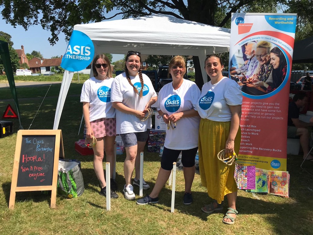 a group of female volunteers attending an outdoor stand with oasis logo